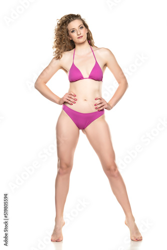 Young blond woman in bikini swimsuit standing on a white background