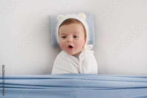 newborn yawns, yawning cute newborn baby lying in bed trying to sleep. Baby sleeplessness concept.
