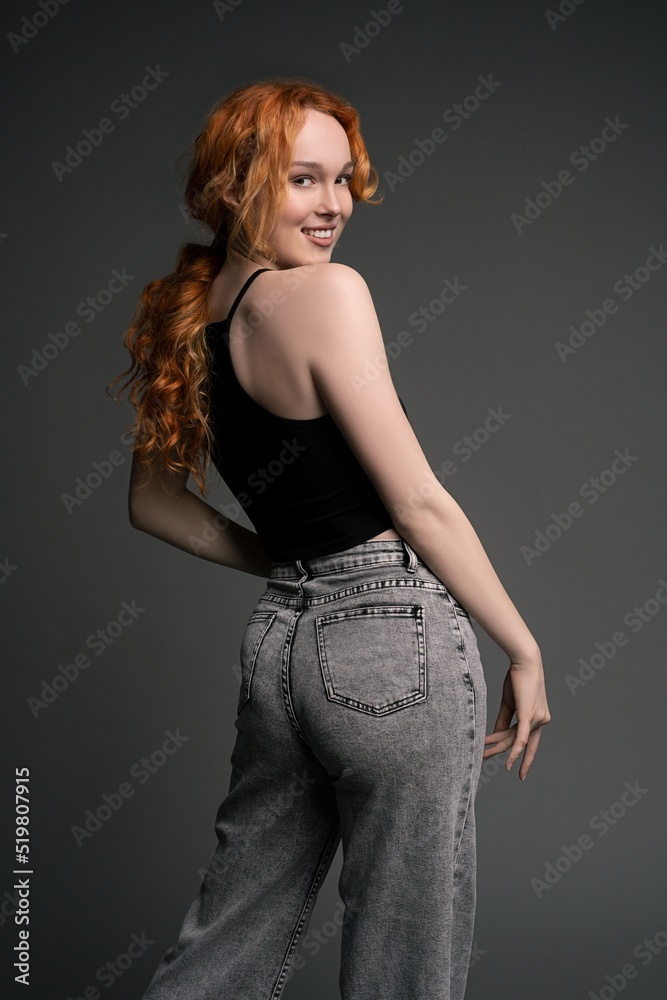 Confident young woman standing in gray studio with happy emotion Confident young woman standing in gray studio with happy emotion