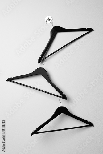 Fototapeta Empty black clothes hangers on white wall