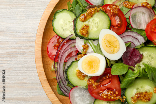 Tasty salad with vegetables and quail eggs on wooden table, top view