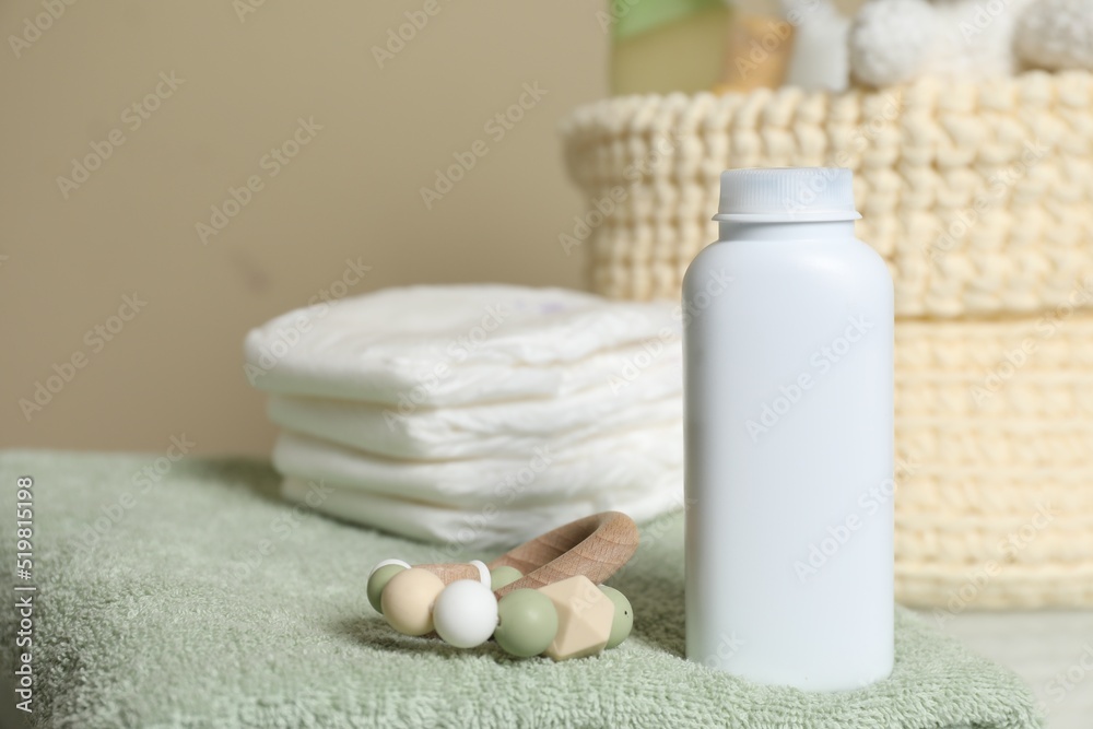 Bottle of dusting powder, wooden toy, soft towel and diapers on beige background, space for text. Baby cosmetic product Bottle of dusting powder, wooden toy, soft towel and diapers on beige background, space for text. Baby cosmetic product