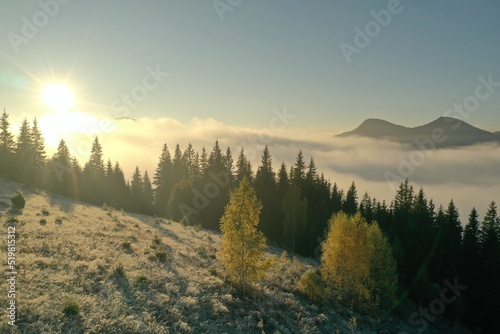 Sun shining over slope covered with hoarfrost in misty mountains. Drone photography