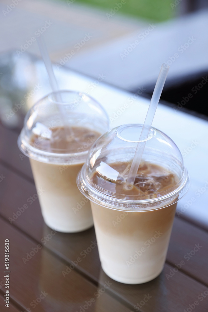 Plastic takeaway cups of delicious iced coffee on table in outdoor cafe