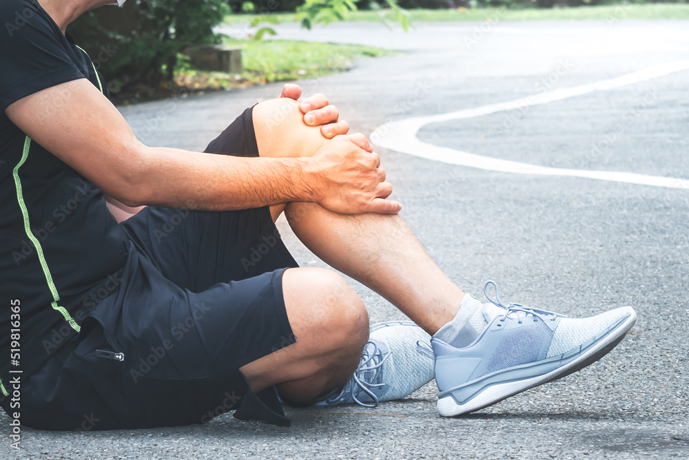 Asian handsome man is currently having a knee injury During  exercise in the park, due to osteoarthritis, to people health care and exercise concept.