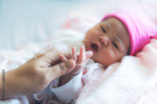 Blur images of mother is holding hand of baby newborn daughter is 7-day-old, is lying on bed, to family and newborn concept.