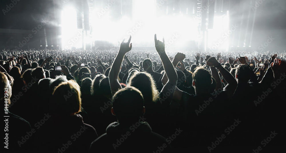 Obraz premium A lot of people raised up hands at the concert event. Fans arms against the stage light.