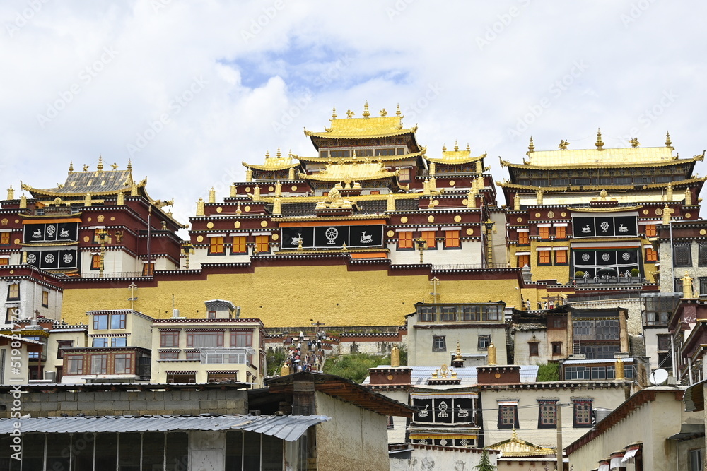 The colorful rooflines of the buildings at the Songzanlin monastery in Shangri-La, China - contrasting against the clear blue sky and adorned with many flags