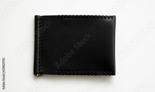 Black men's money clip handmade leather wallet for cards lies on a white table. Leather goods and accessory.