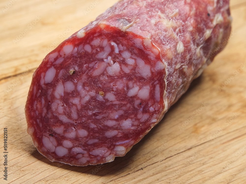 Smoked sausage on a wooden background close-up shot. A piece of sausage on a wooden surface. Smoked sausage on a wooden background close-up shot. A piece of sausage on a wooden surface.