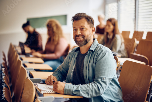 Happy mature man attending a class at university and looking at camera.