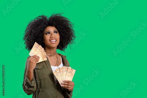 woman holding money, young smiling woman holding Brazilian money, green background photo