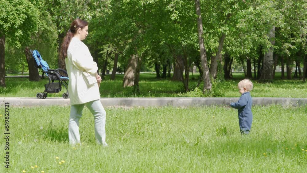 Mother and child walk in the park in summer, happy kid playing with mom on green grass on a sunny day. Mother and child walk in the park in summer, happy kid playing with mom on green grass on a sunny day.
