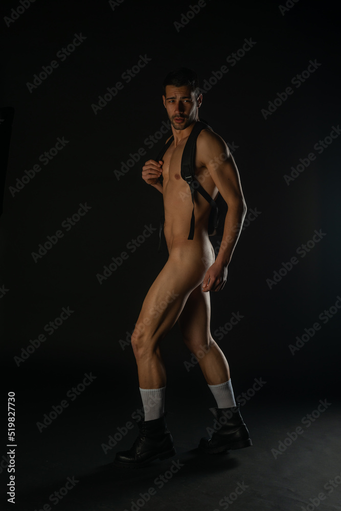 Sexy nude man posing in a dark studio in black boots with a black backpack  Stock Photo | Adobe Stock