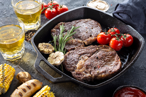 Grilled ribeye steak on frying cast iron Grill pan on dark background
