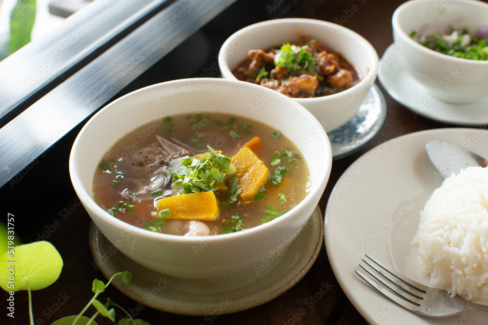 Food set white rice pumpkin soup spicy pork and slice mixed vegetable on wooden table with spoon fork
