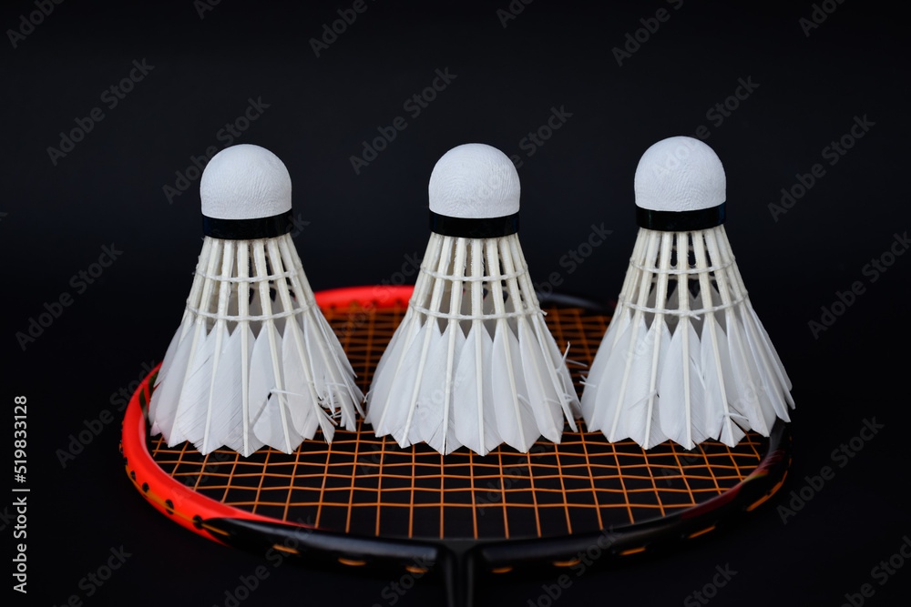 White cream badminton shuttlecock and badminton rackets on dark floor of indoor badminton court, soft and selective focus, concept for badminton sport lovers around the world
