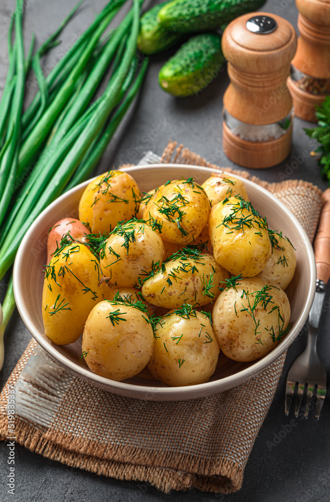 Boiled potatoes with dill and butter close-up on a dark background. Side view, vertical Boiled potatoes with dill and butter close-up on a dark background. Side view, vertical