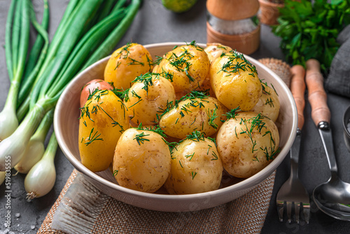 Boiled new potatoes with dill and butter on a dark background. Side view, close-up