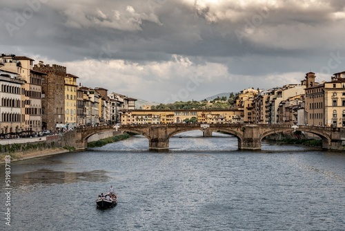 View of Florence with "Ponte Vecchio" in the background and tourists sailing on the Arno river