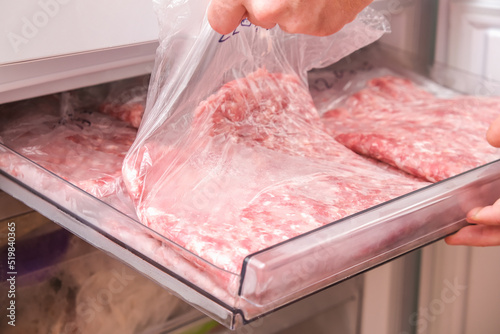 A man puts minced pork and beef in the freezer in serving bags for long storage.