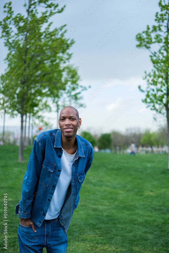 Half-length portrait of young non-binary man in park outdoors smiling