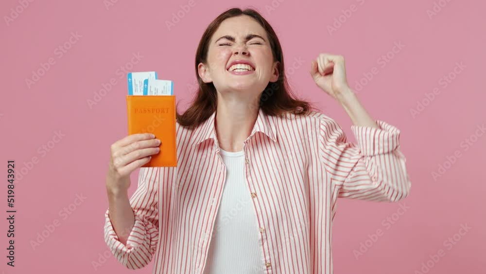 Traveler tourist woman in shirt hold passport boarding pass tickets do winner gesture isolated on plain light pink background studio Passenger travel abroad weekends getaway Air flight journey concept Traveler tourist woman in shirt hold passport boarding pass tickets do winner gesture isolated on plain light pink background studio Passenger travel abroad weekends getaway Air flight journey concept