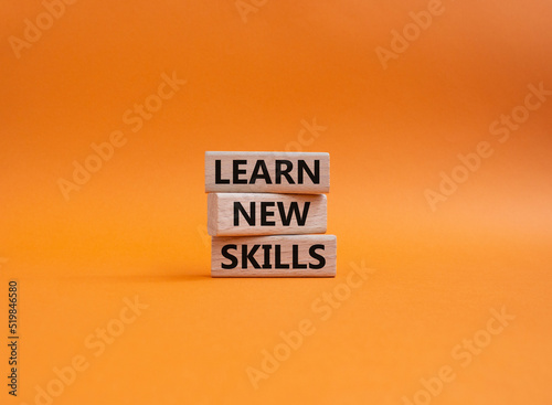 Learn new skills symbol. Concept words 'Learn new skills' on wooden blocks. Beautiful orange background. Business and Learn new skills concept. Copy space.
