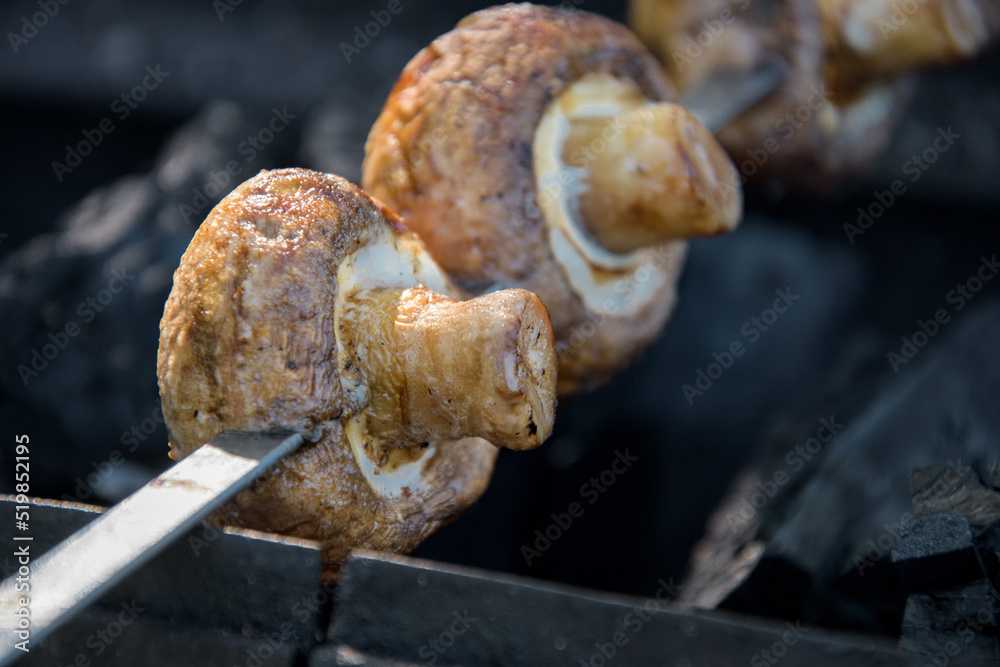 White mushrooms champignons are planted on skewers lie on the grill White mushrooms champignons are planted on skewers lie on the grill