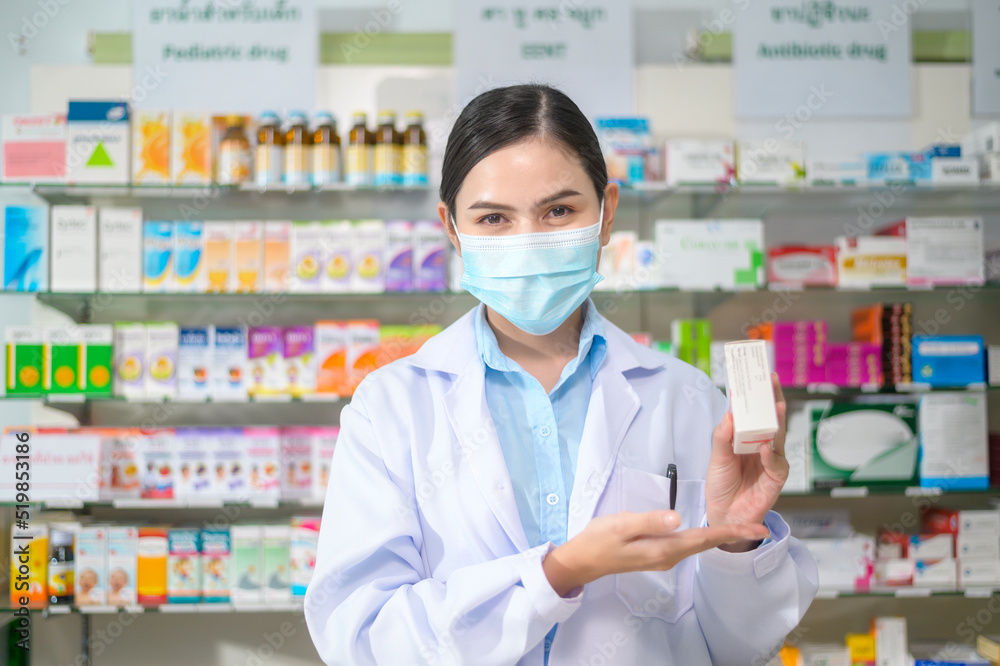 Portrait of female pharmacist wearing face mask in a modern pharmacy drugstore.