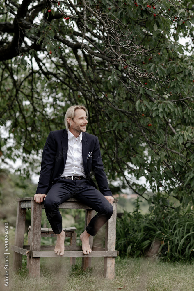businessmann sitzt auif holztisch im garten businessmann sitzt auif holztisch im garten