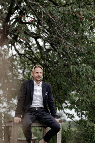 Businessmann sitzt auif Holztisch im Garten