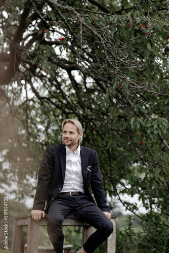 Businessmann sitzt auif Holztisch im Garten