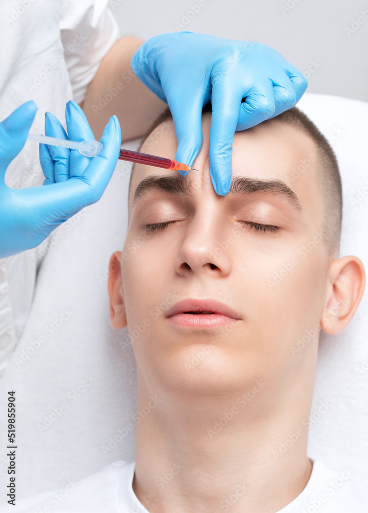 Men's cosmetology. Beautician makes a man a rejuvenation injection procedure of a handsome young man in a beauty salon. Men's cosmetology. Beautician makes a man a rejuvenation injection procedure of a handsome young man in a beauty salon.