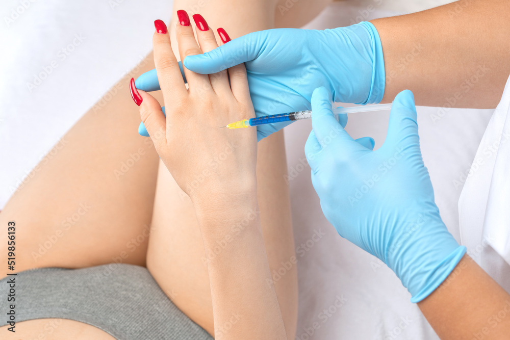 The cosmetologist makes injections against sagging on the hands of a woman. Women's cosmetology, skin care.