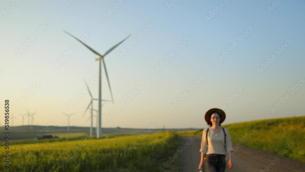 Young woman walking near a field with alternative energy turbines Young woman walking near a field with alternative energy turbines
