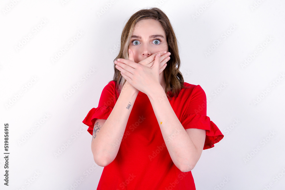 young caucasian woman wearing red T-shirt over white background shocked covering mouth with hands for mistake. Secret concept. young caucasian woman wearing red T-shirt over white background shocked covering mouth with hands for mistake. Secret concept.