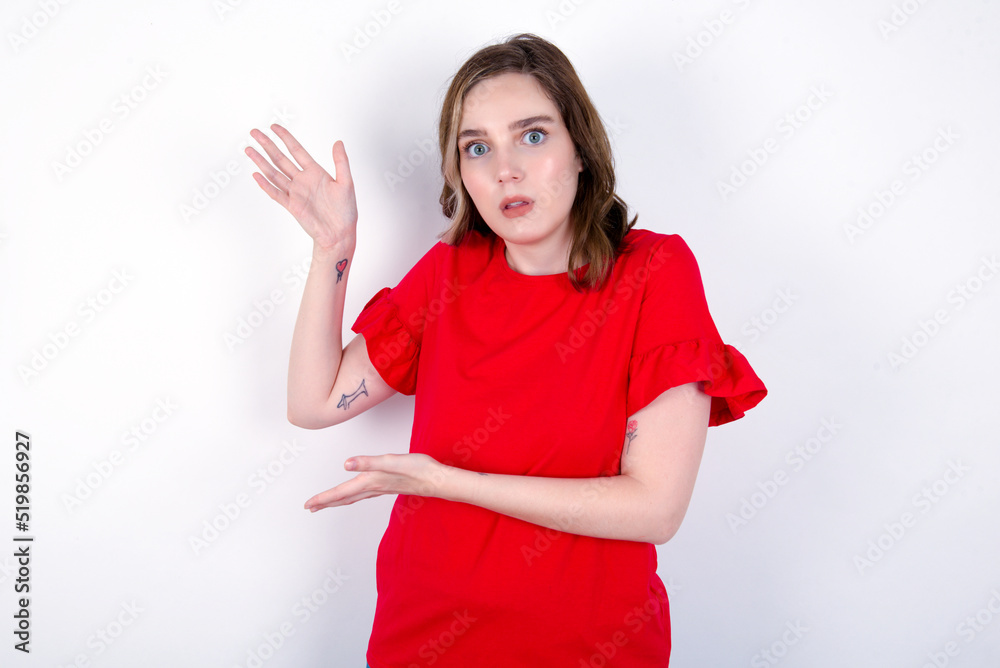young caucasian woman wearing red T-shirt over white background pointing aside with both hands showing something strange and saying: I don't know what is this. Advertisement concept. young caucasian woman wearing red T-shirt over white background pointing aside with both hands showing something strange and saying: I don't know what is this. Advertisement concept.