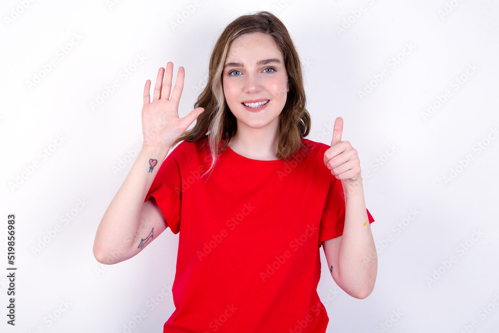 young caucasian woman wearing red T-shirt over white background showing and pointing up with fingers number six while smiling confident and happy. young caucasian woman wearing red T-shirt over white background showing and pointing up with fingers number six while smiling confident and happy.