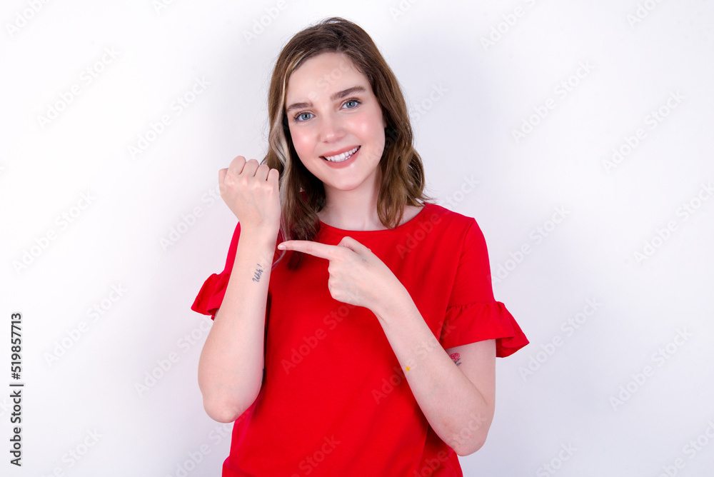 young caucasian woman wearing red T-shirt over white background  In hurry pointing to wrist watch, impatience, looking at the camera with relaxed expression