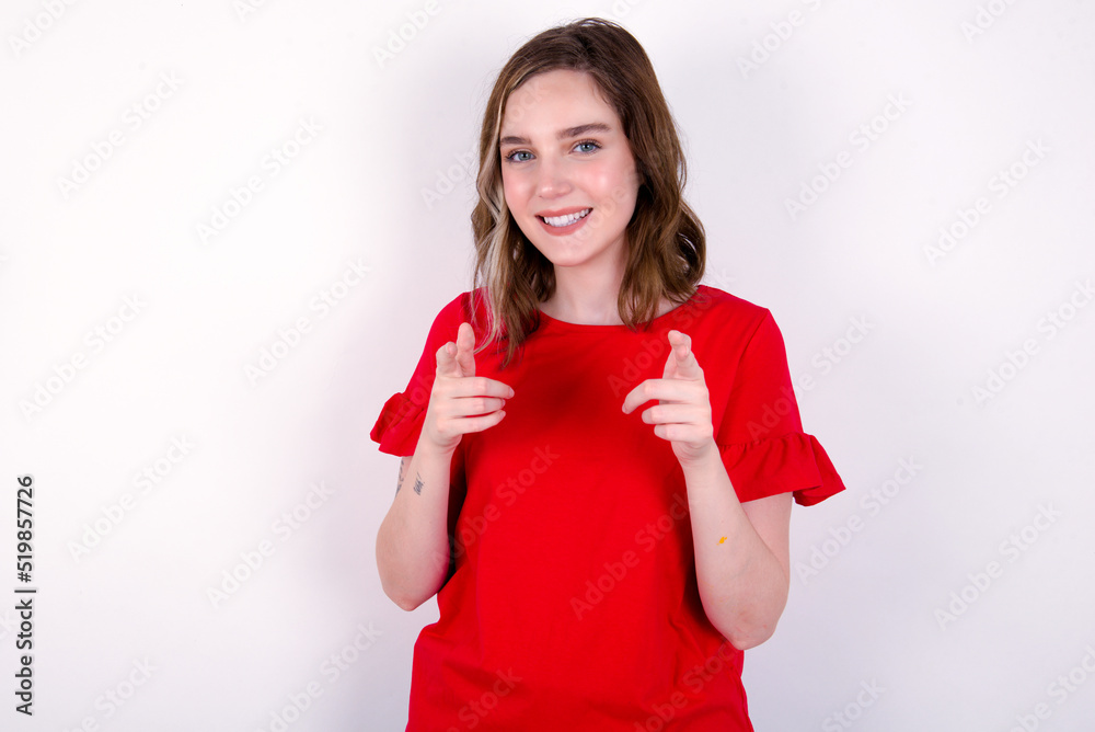 young caucasian woman wearing red T-shirt over white background pointing fingers to camera with happy and funny face. Good energy and vibes. young caucasian woman wearing red T-shirt over white background pointing fingers to camera with happy and funny face. Good energy and vibes.