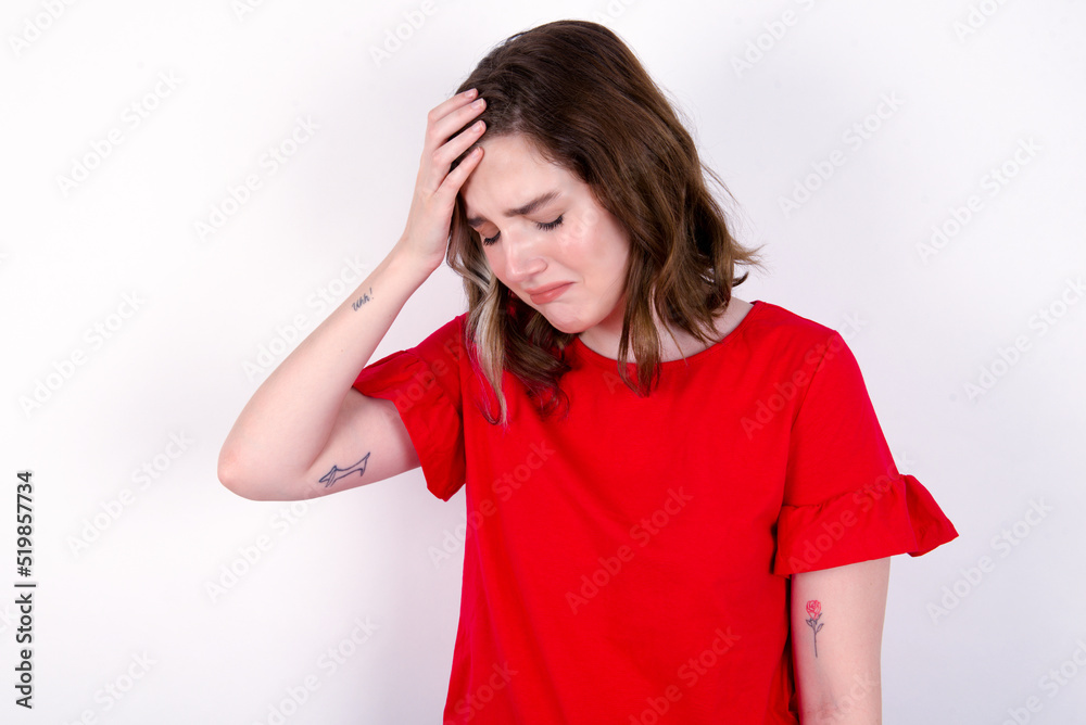 A very upset and lonely young caucasian woman wearing red T-shirt over white background crying, A very upset and lonely young caucasian woman wearing red T-shirt over white background crying,