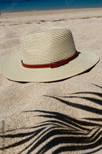 wicker hat and shadow from a palm tree on the sand