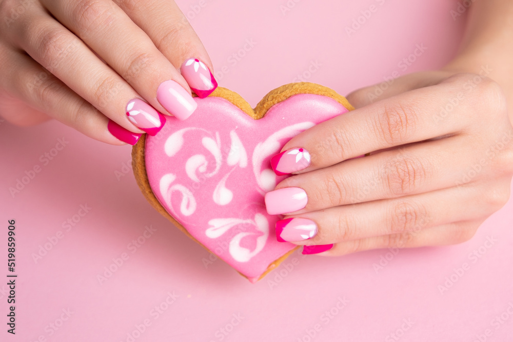Beautiful female hands with pink manicure nails, flowers design, holding candy in shape of heart
Beautiful female hands with pink manicure nails, flowers design, holding candy in shape of heart