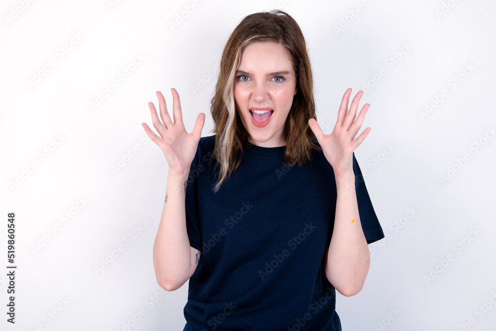 Φωτογραφία Crazy outraged young caucasian woman wearing black T-shirt over white background screams loudly and gestures angrily yells furiously