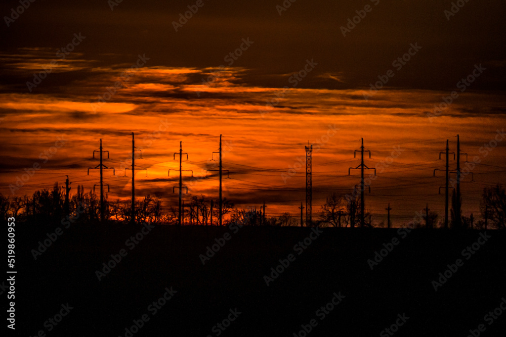 The beginning of the sunset of the big sun in the evening against the background of the horizon sky and electric antennas