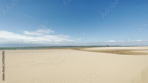 (Slow-Mo) Sanlucar de Barrameda beach in Spain. This beach is formed by water from the mouth of the Gualdalquivir River and the Atlantic Ocean, with the 'Coto Doñana' National Park in front. photo