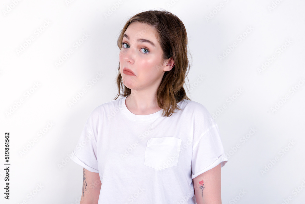 young caucasian woman wearing white T-shirt over white background with snobbish expression curving lips and raising eyebrows, looking with doubtful and skeptical expression, suspect and doubt. young caucasian woman wearing white T-shirt over white background with snobbish expression curving lips and raising eyebrows, looking with doubtful and skeptical expression, suspect and doubt.