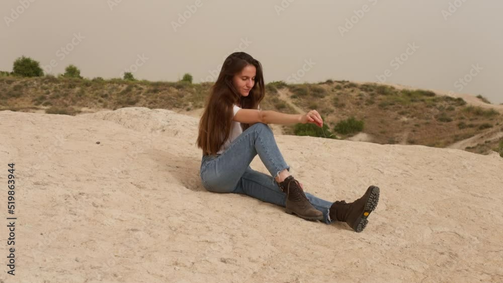 Cute young woman with dark hair in jeans sits on rocky hill slope in Cappadocia Cute young woman with dark hair in jeans sits on rocky hill slope in Cappadocia