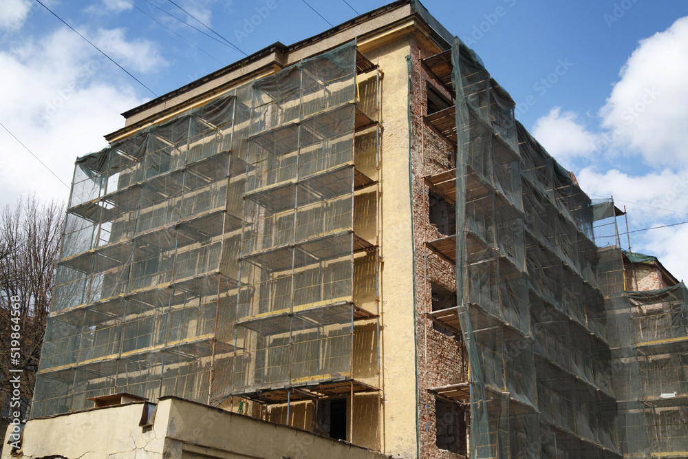 Renovated old building in scaffolding covered with a grid.